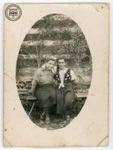 Dwie młode kobiety na ławeczce przed drewnianym budynkiem